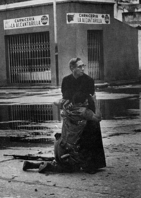 1962. Luis Padilla atya vonszolja el az utcáról a mesterlövész által halálosan megsebesített katonát Puerto Cabello-ban Venezuelában..jpg