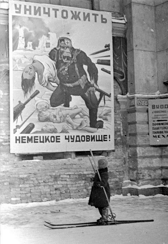 1941_december_a_russian_child_on_skis_reads_a_soviet_propaganda_poster_stating_kill_german_monster_leningrad_su.jpg