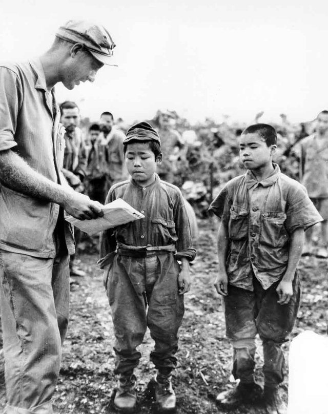 1945_marine_first_lieutenant_hart_h_spiegal_of_topeka_kansas_uses_sign_language_as_he_tries_to_strike_up_a_conversation_with_two_tiny_japanese_soldiers_captured_on_okinawa.jpg