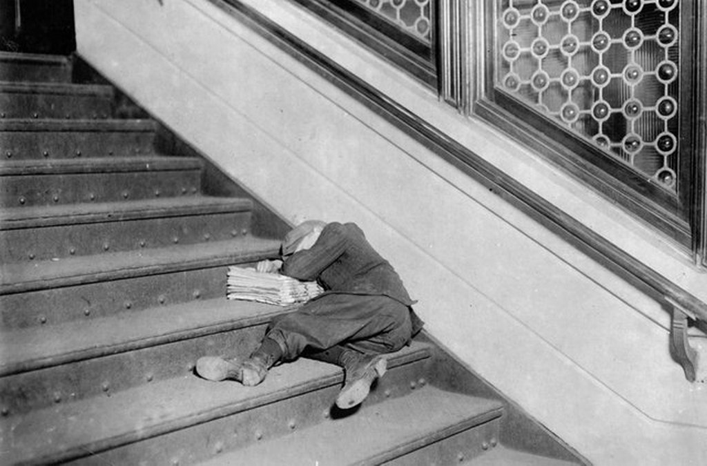 1912_a_young_newsboy_asleep_on_a_set_of_stairs_with_his_papers_in_jersey_city_new_jersey.jpg