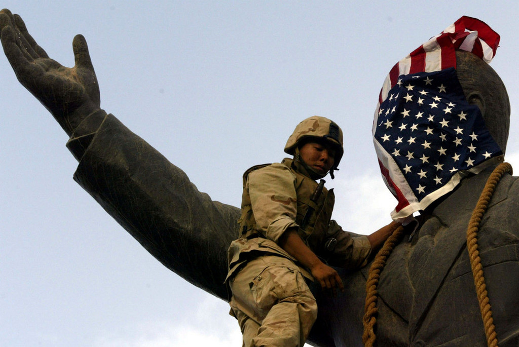 2003_aprilsi_u_s_marine_covers_the_face_of_a_statue_of_iraqi_president_saddam_hussein_with_a_u_s_flag_in_baghdad_iraq.jpeg