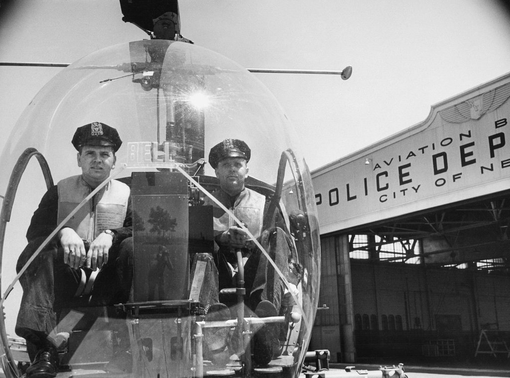 1953_with_the_photographer_sam_falk_visible_on_the_front_of_the_helicopter_s_bubble_shield_two_police_officers_sat_ready_at_floyd_bennett_field_in_brooklyn_to_begin_a_patrol.jpg