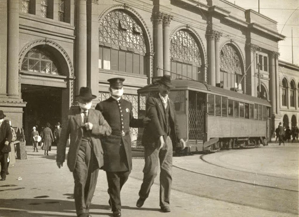 1918_a_police_officer_escorts_two_men_by_their_arms_one_without_a_mask_near_the_ferry_building_in_downtown_san_francisco_spanish_flu_pandemic.jpg