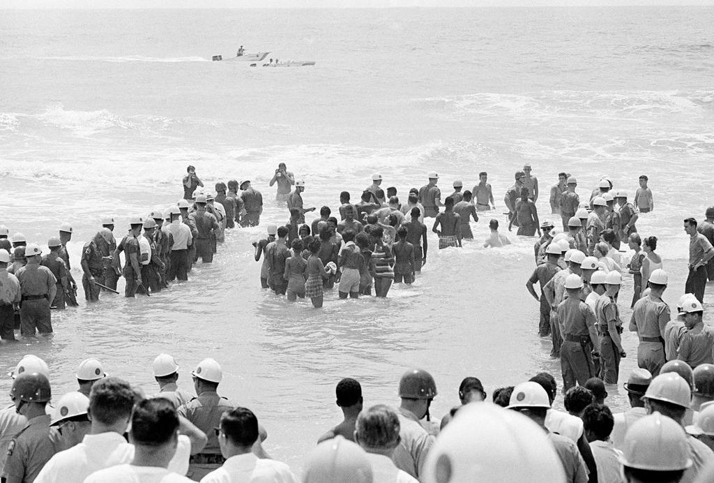 1964_a_group_of_desegregationist_demonstrators_are_guarded_by_a_heavy_surrounding_force_of_police_officers_during_a_wade-in_at_st_augustine_beach_florida.jpg
