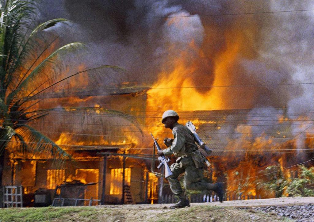 1968_a_u_s_solider_runs_past_a_burning_house_in_saigon.jpg