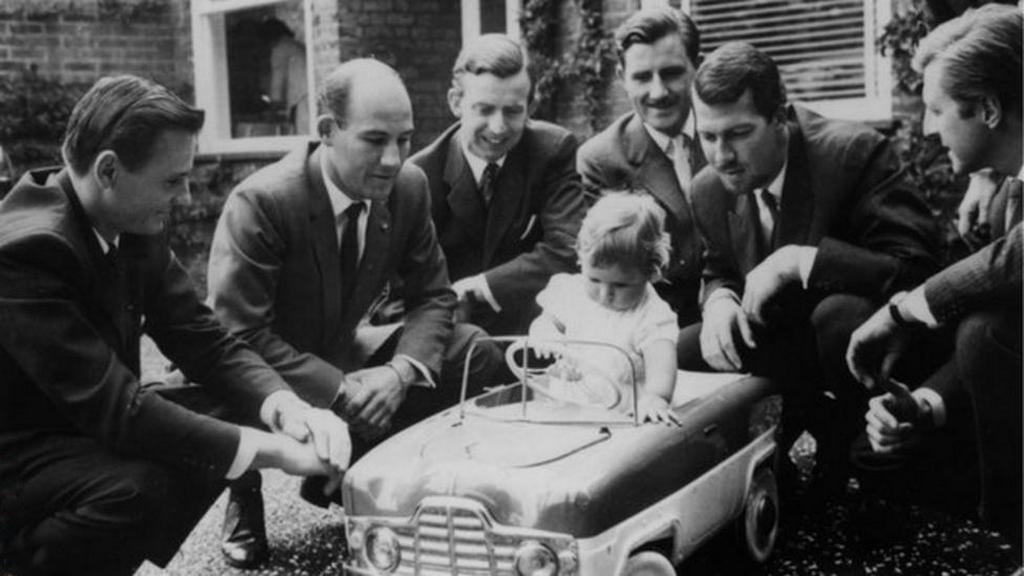 1961_f1_drivers_bruce_mclaren_stirling_moss_tony_brooks_graham_hill_jo_bonnier_and_wolfgang_von_trips_the_toddler_in_the_car_is_1996_f1_world_champion_damon_hill.jpg