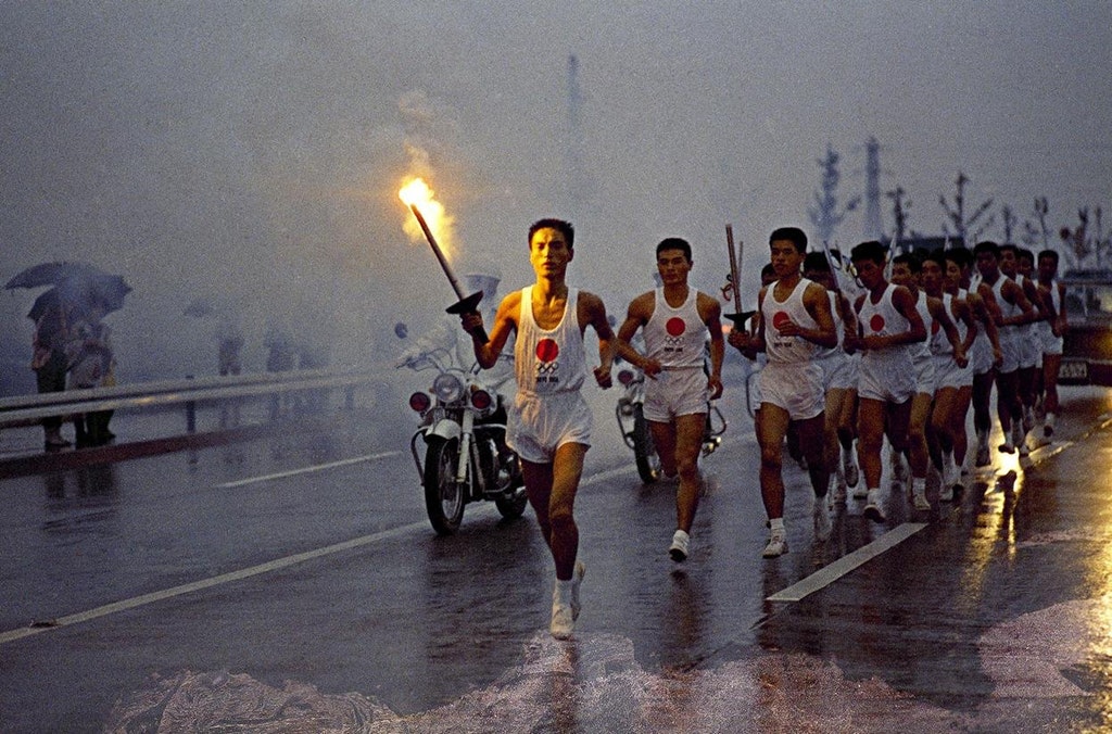 1964_japanese_torchbearers_run_through_the_rain_on_their_way_to_olympic_stadium_in_tokyo.jpg