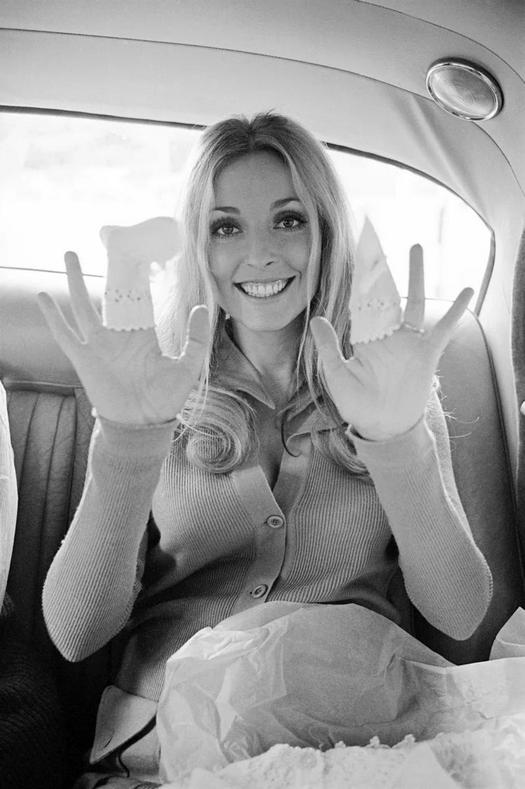 1969_sharon_tate_showing_off_the_baby_clothing_she_had_bought_in_london.jpg