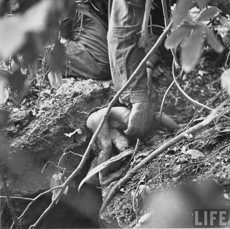 1944. Saipan, Csendes-óceáni hadszintér. Amerikai tengerészgyalogos emeli ki egy beomlott óvóhelyről egy életben lévő benszülött kisbaba testét..jpg