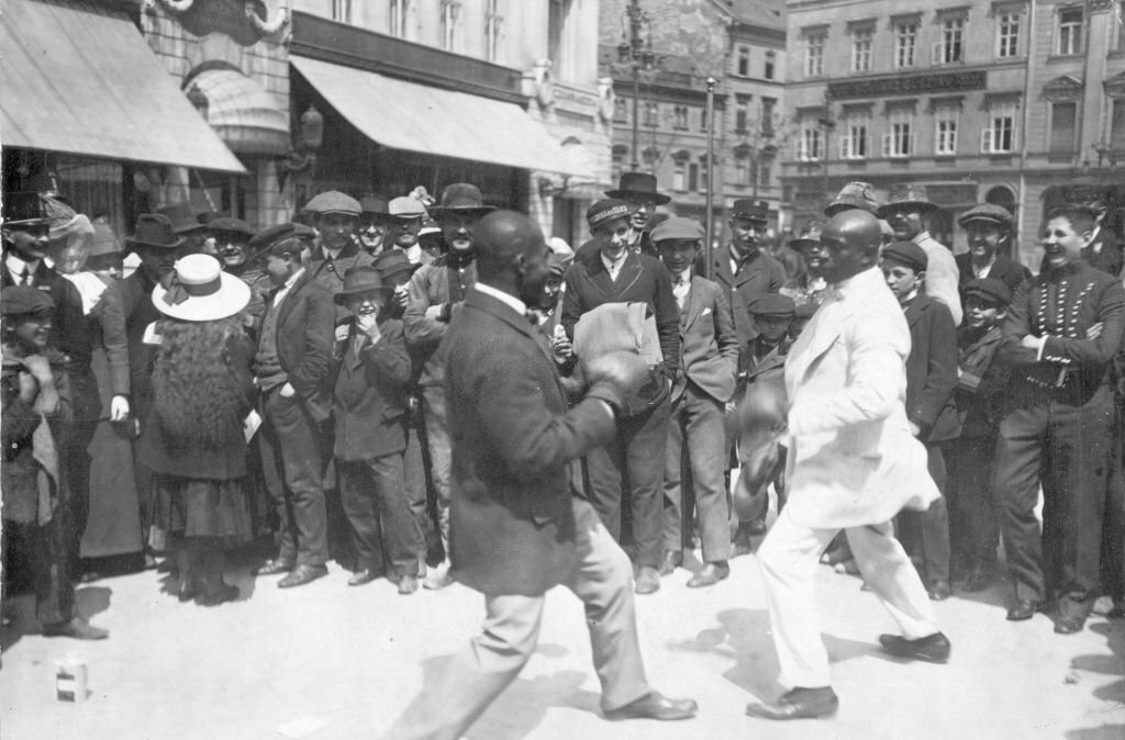 1930_two_black_boxers_put_on_a_boxing_performance_in_the_street_on_childrens_day_in_budapest.jpg