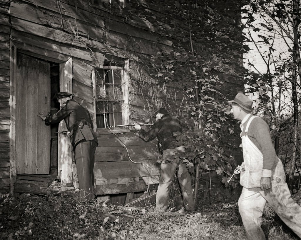 1940-es_evek_policemen_and_posse_armed_with_guns_approaching_abandoned_shack_searching_for_escaping_crooks_hiding_inside.jpg