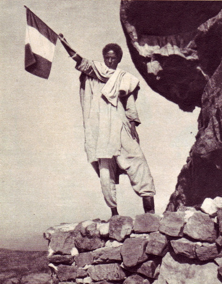 1935. Csonkolt etióp katona olasz zászlót lenget. A második olasz abesszín háborúban azokat az abesszínokat, akik az olaszok mellé álltak, jobb kezük és bal lábfejük levágásával bűntették..jpg