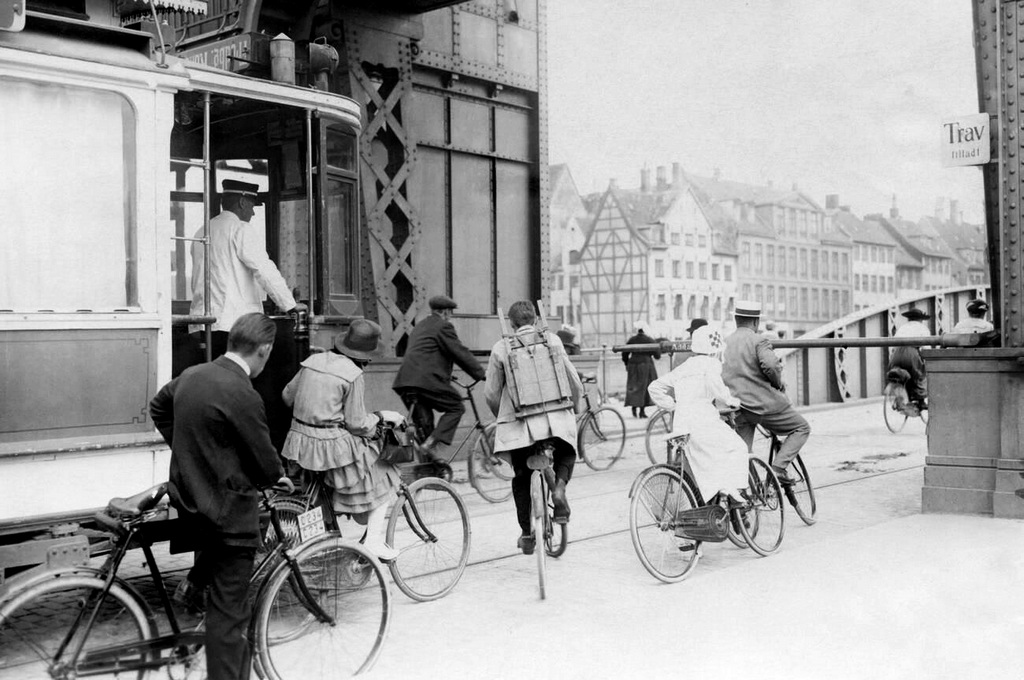 1914_men_and_women_on_bicycles_ride_past_a_tram_and_pass_a_barrier.jpg