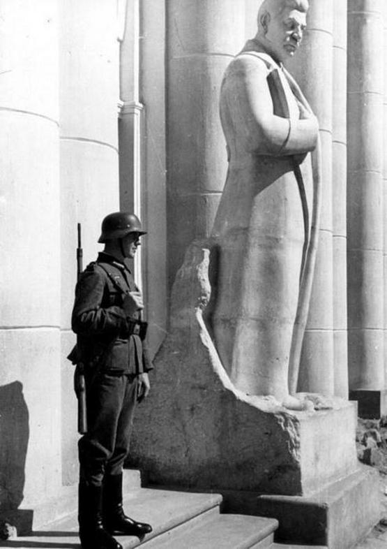 1941_german_soldier_standing_next_to_a_stalin_statue_in_occupied_novgorod_ussr.jpeg