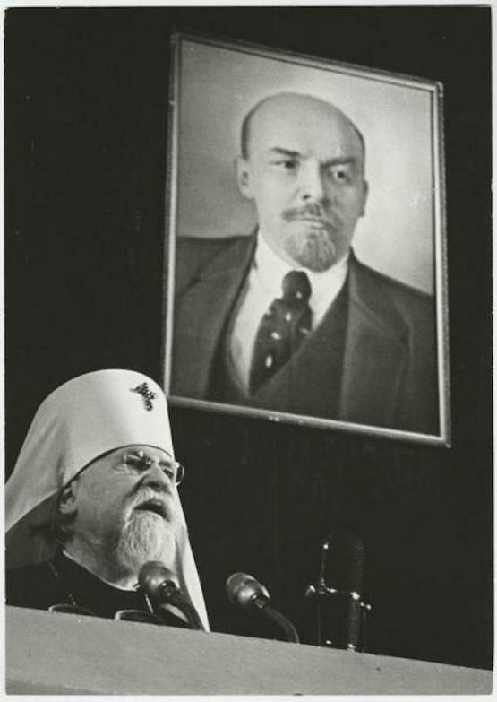 1960_an_orthodox_priest_preaching_infront_of_a_portrait_of_lenin.jpeg