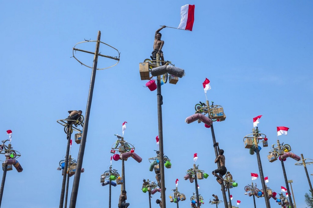 2024_08_17_participant_waves_a_national_flag_after_climbing_to_the_top_of_a_greased-pole_to_retrieve_prizes_as_part_of_independence_day_celebrations_in_jakarta_indonesia_ap_photo_tatan_syuflana.jpg