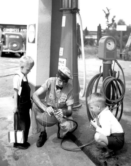 1940_a_service_station_attendant_helps_two_boys_get_their_football_pumped_up_to_pressure_with_air_houston_usa.jpeg