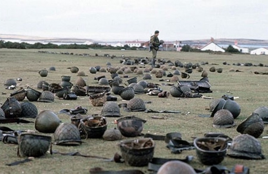 1982. május. Brit katona nézegeti az eldobált argentin sisakokat a Goose Green-i csata után a Falkland-szigeten..jpg