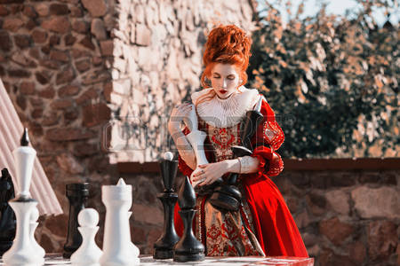 76175255-the-red-queen-is-playing-chess-red-haired-woman-in-a-chic-vintage-dress-fashion-photo.jpg