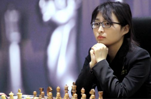 game-3-champion-ju-wenjun-under-pressure-pawn-behind-at-chessboard-in-chair.jpg