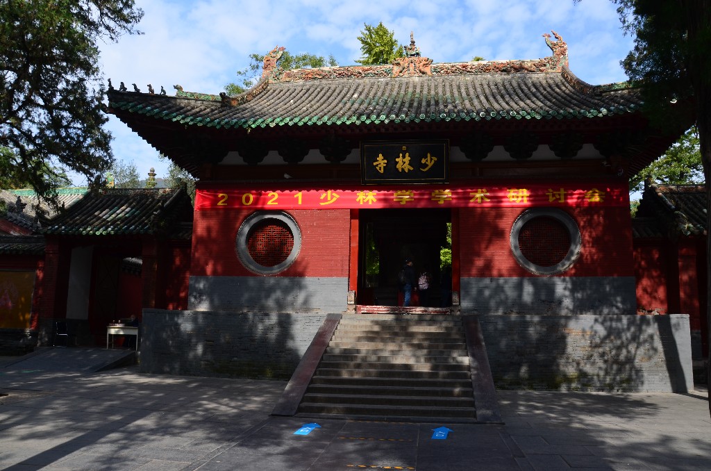 Shanmen - A bejárati kapu 1735-ben épült az arany betűs ‘Shaolin Templom‘ feliratot Kangxi császárnak (Qing-dinasztia) tulajdonítják<br />A 3 karakter: SHAO LIN SI (Shaolin templom). A tábla mérete 90x193 cm. A LIN karakter fölé Kang Xi császár pecsétje van kivésve: „Kang Xi Yu Bi Zhi Bao‘.