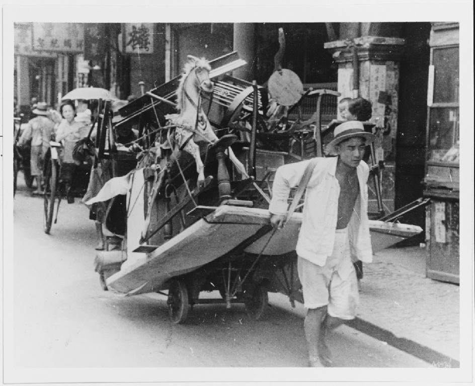 Személyes holmikkal és bútorokkal telepakolt kocsit húz egy férfi, aki a kínai és a japán erők harca elől menekült a sanghaji Nemzetközi Telephelyre 1937 augusztusában