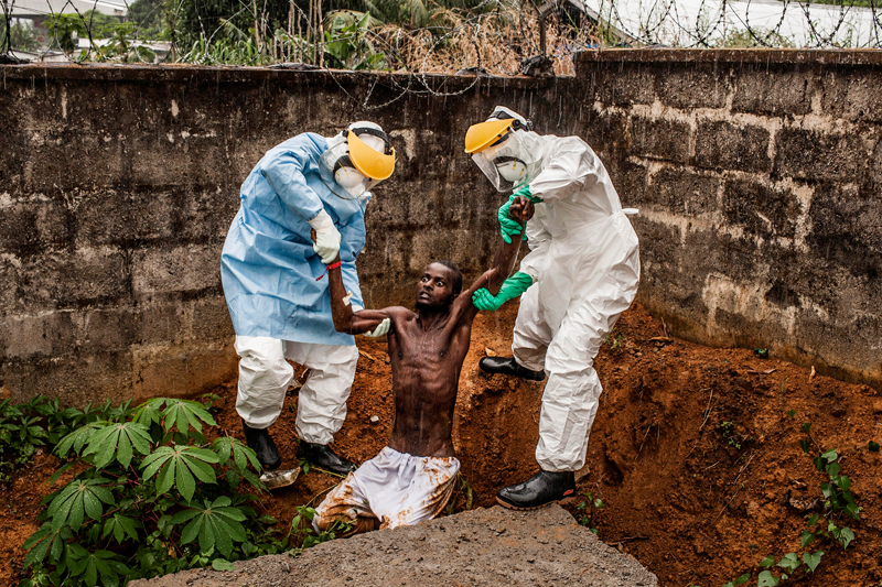 Hír<br />1. díj, sorozat<br />Pete Muller<br />Amerikai Egyesült Államok, Prime a National Geographic / The Washington<br />Post számára<br />A halálos Ebola vírus májusban kezdett ismét áldozatokat szedni Sierra<br />Leonéban. A betegség gyógyíthatatlan, a halálos áldozatok aránya akár a<br />90 százalékot is elérheti. A vírus nagyon fertőző, és rendkívüli<br />óvintézkedésekre van szükség a betegek ápolása és az áldozatok<br />eltemetése közben. Az év végére az Ebola 2758 ember halálát okozta<br />Sierra Leonéban. A kór a szomszédos Guineában és Libériában is<br />pusztított, a három országban összesen 7880 áldozatot követelt 2014-ben.<br />Sírásók pihennek a nap végén a King Tom temetőben Freetownban, Sierra