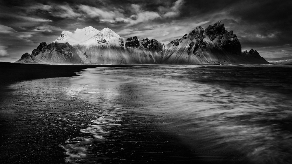 Az első fények <br />Fekete-fehér természetfotók kategória 3. díj<br />A Vesturhorn Izland egyik leglátványosabb, mesebeli és vadregényes hegye. Egyik lábánál fekete homokpartot találunk, amely dagálykor rendszeresen víz alá kerül.<br />Fotó: Barbalics Nándor