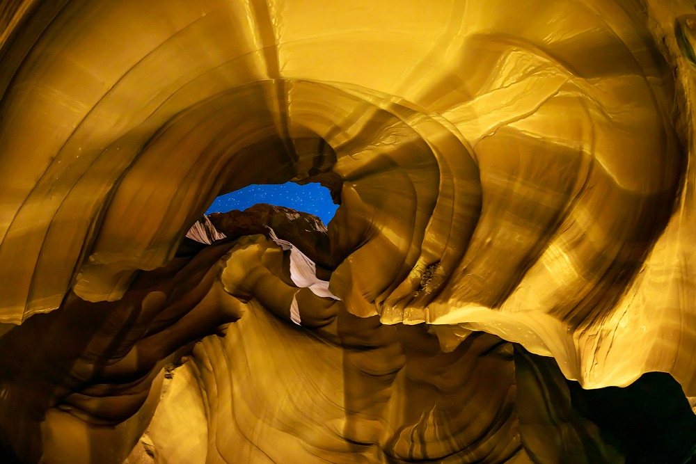 Csigaház<br />Ezt a fotót az egyesült államokbeli Antilop-kanyonban készítettem az esti órákban. Köszönhetően a halszemobjektívnek – amely felfelé, a csillagos égbolt irányába volt beállítva – a viszonylag szűk teret teljesen sikerült „befognom”. Az említett hatásból adódóan az oldalsó sziklákból egy csigaházforma rajzolódott ki számomra, amit a földre irányított lámpák reflexiója, valamint a viszonylag hosszabb expozíció emel ki.<br />Fotó: Laki Zoltan