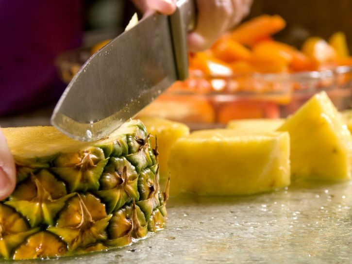 slicing-a-freshly-cleaned-whole-pineapple-atop-a-clean-glass-cutting-board-725x544.jpg