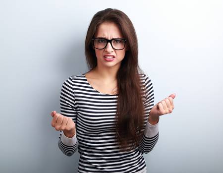 49104186-nervous-angry-young-woman-in-glasses-with-aggressive-negative-face-showing-fists-on-blue-background.jpg