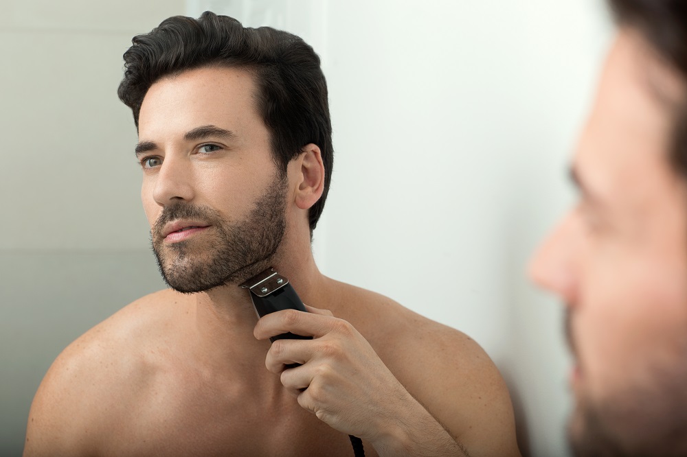 mens-beard-guide-life-style-model-looking-into-mirror-grooming-beard-electric-razor-in-bathroom.jpg