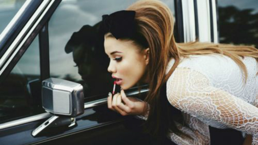 girl-looking-at-a-rearview-mirror-and-putting-a-lipgloss-on1.jpg