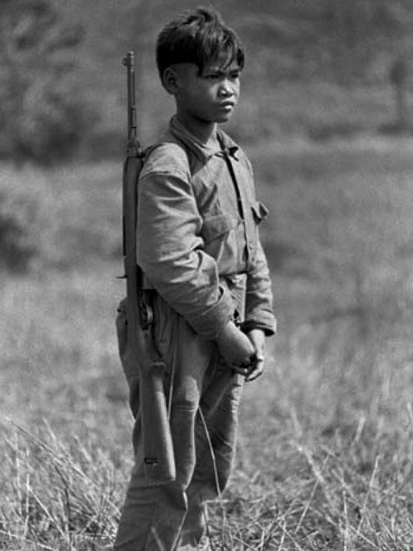 Laoszi katonafiú áll őrt az észak-vietnámi határon, vállán egy M–1