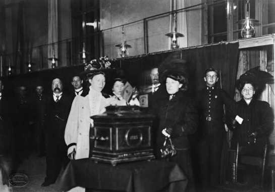 57041_f_rste_kvinne_legger_stemmeseddelen_i_urnen_ved_valget_i_1910.jpg