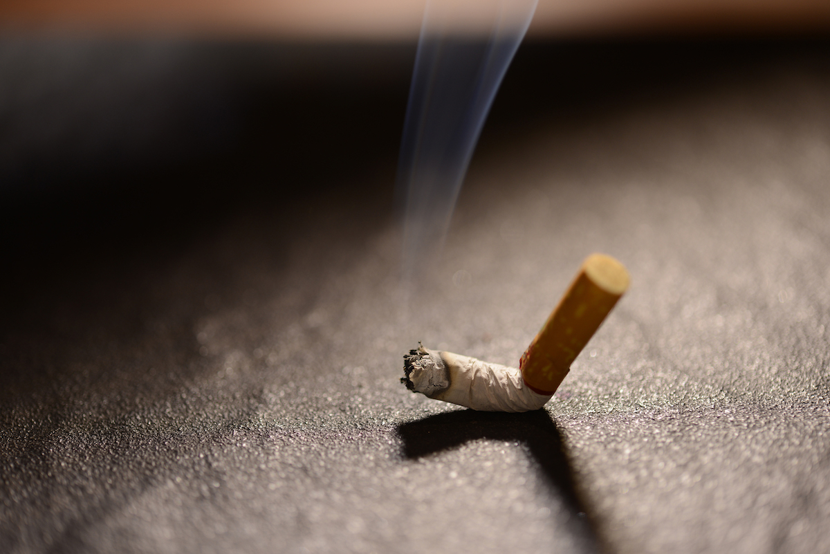 lit-cigarette-butt-with-smoke-on-the-ground-plurdk7.jpg